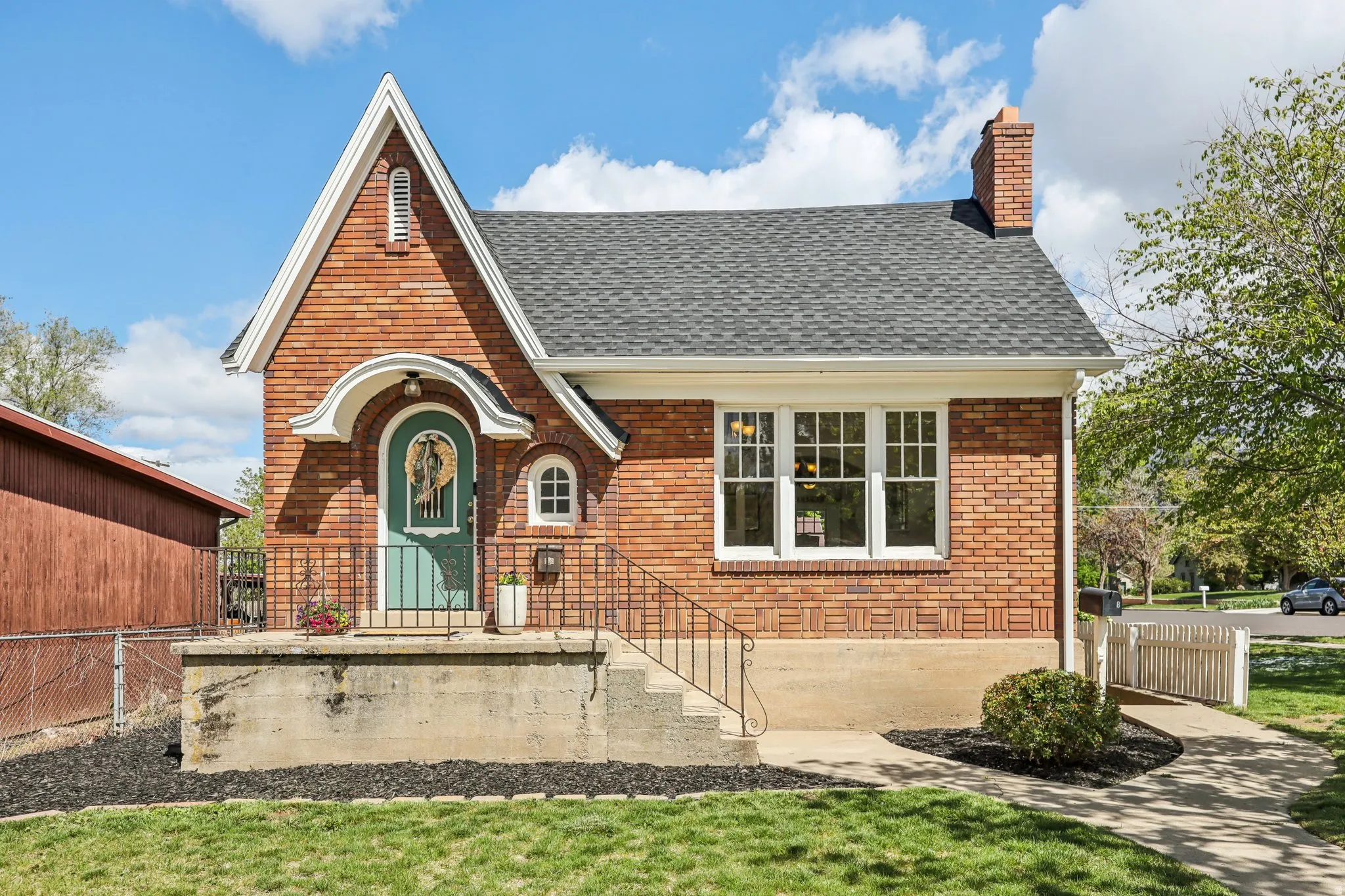 View of front facade with brick siding, a shingled roof, and a chimney
