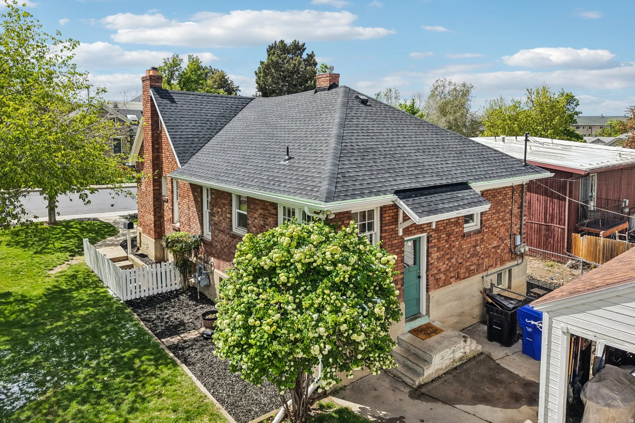 Back of house with a shingled roof, a chimney, brick siding, and entry steps