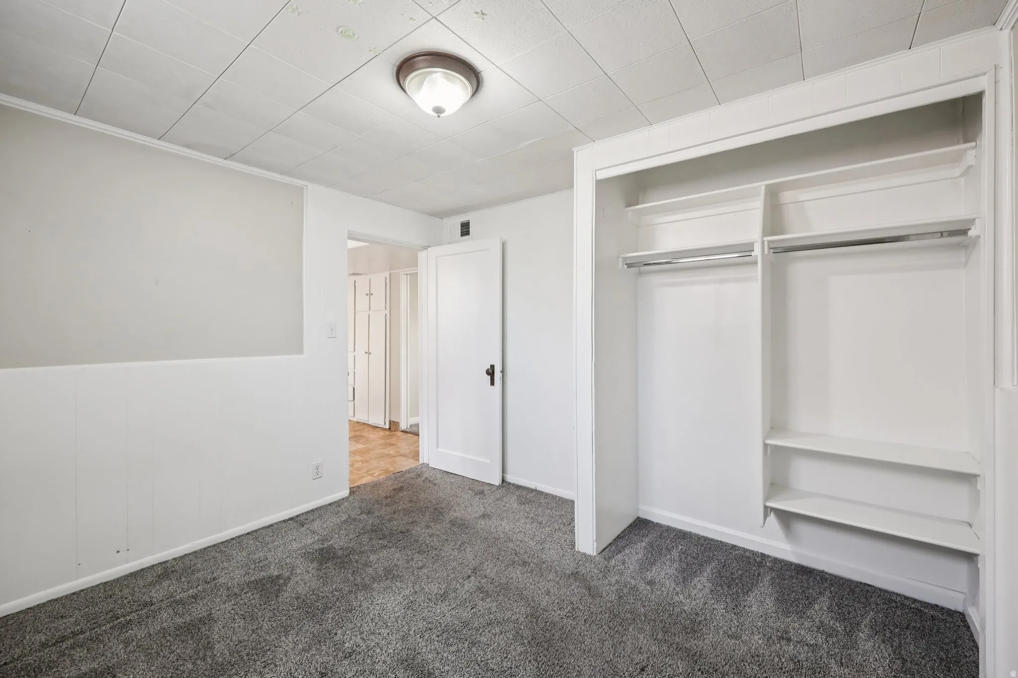 Unfurnished bedroom featuring dark carpet and a closet
