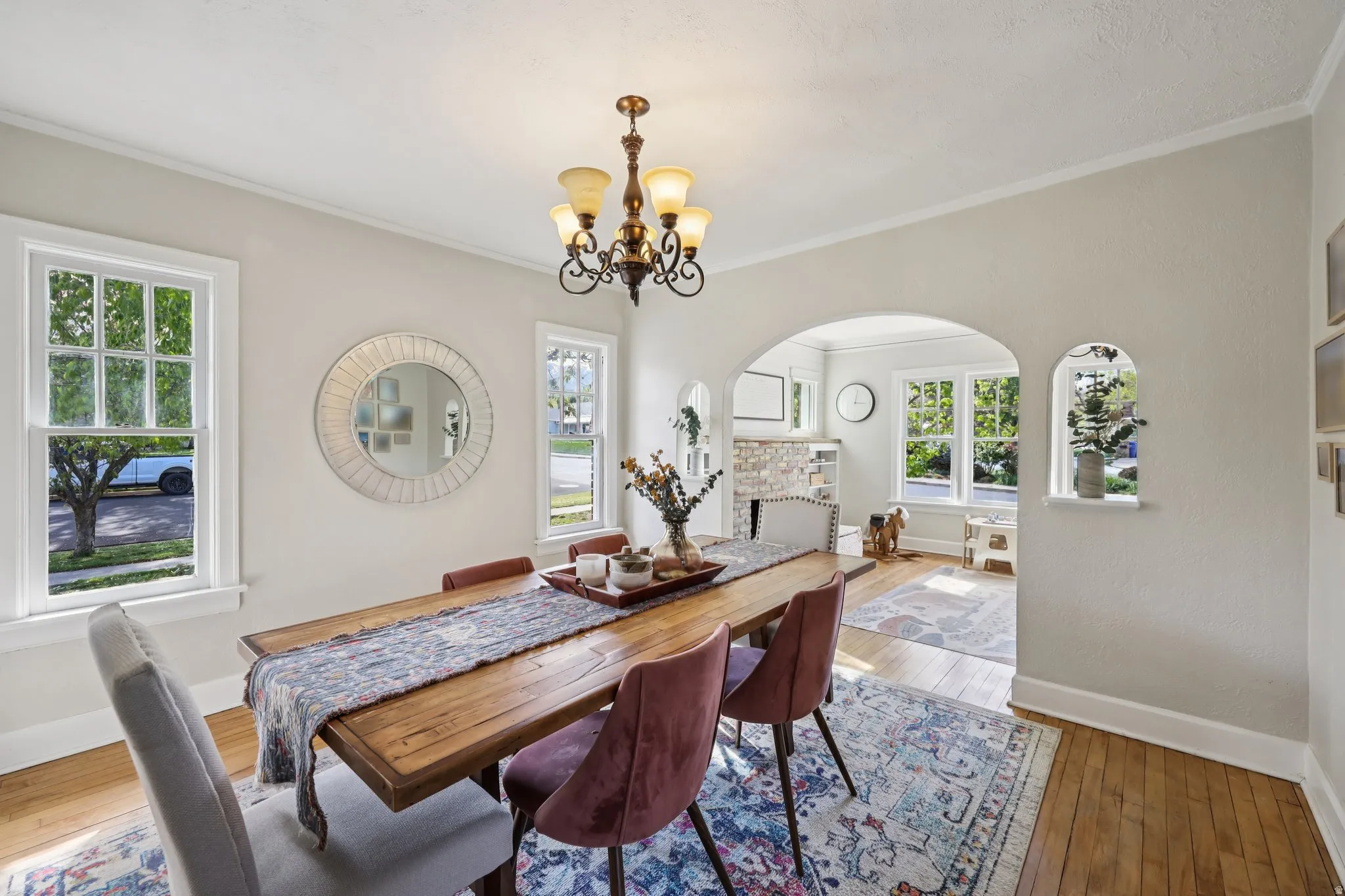 Dining room with light wood-style floors, hanging lights, arched walkways, and crown molding