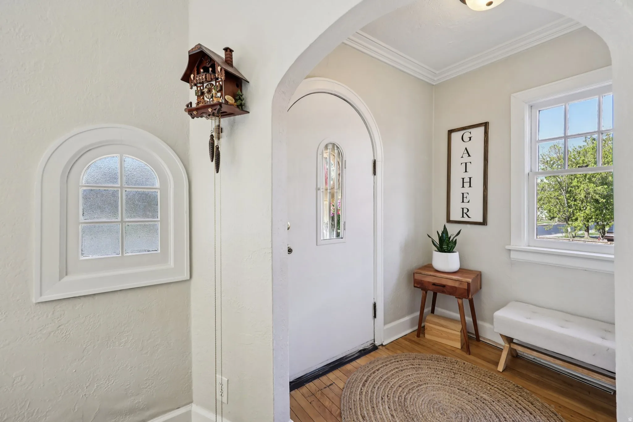 Foyer entrance with light wood-style floors, arched walkways, and ornamental molding