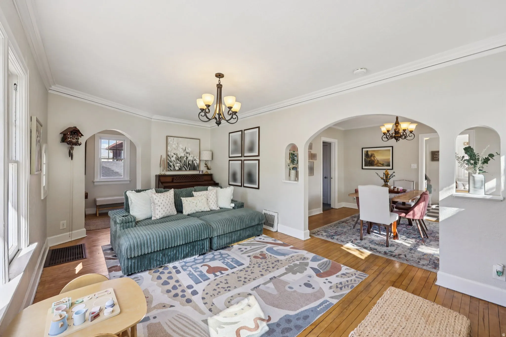 Living room with a chandelier, arched walkways, hardwood / wood-style floors, and crown molding