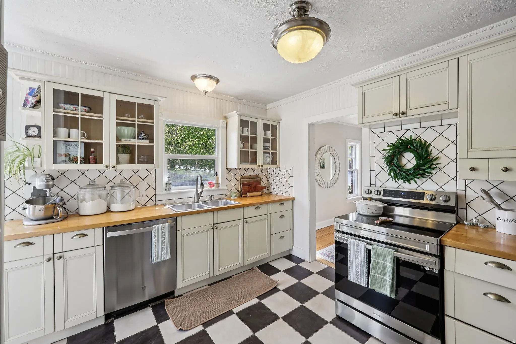 Kitchen featuring butcher block countertops, stainless steel appliances, light floors, tasteful backsplash, and glass fronted cabinets