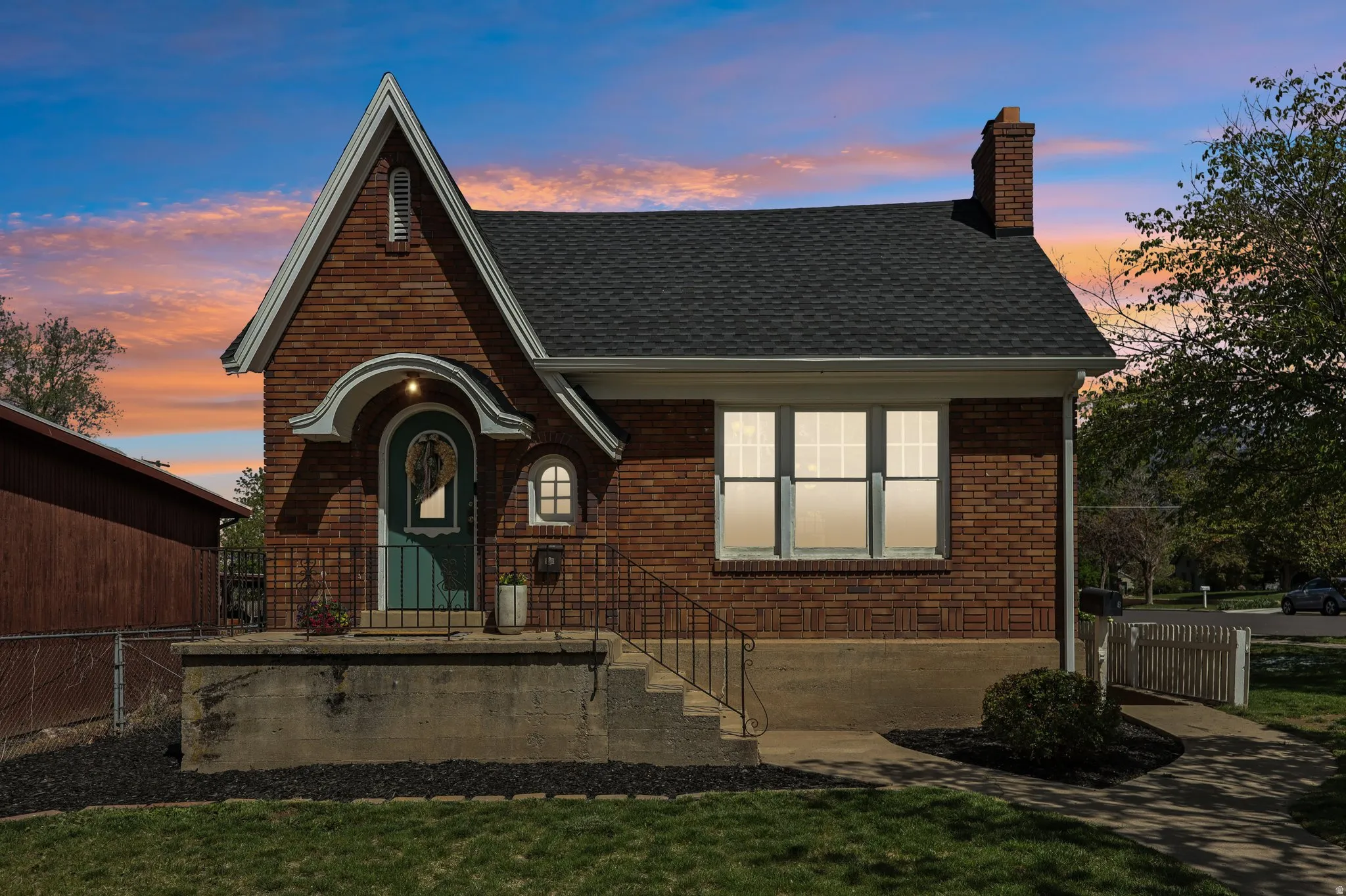View of front of house featuring brick siding, a shingled roof, and a chimney