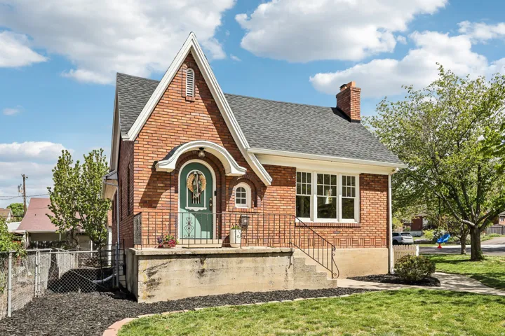 Tudor house with brick siding, a shingled roof, and a chimney