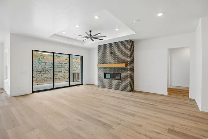 Spacious room featuring wood-finish flooring, a tray ceiling with recessed lighting, and a modern ceiling fan
