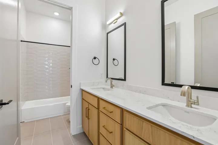 Double vanity with light wood-finish cabinetry, white countertop, and rectangular undermount sinks