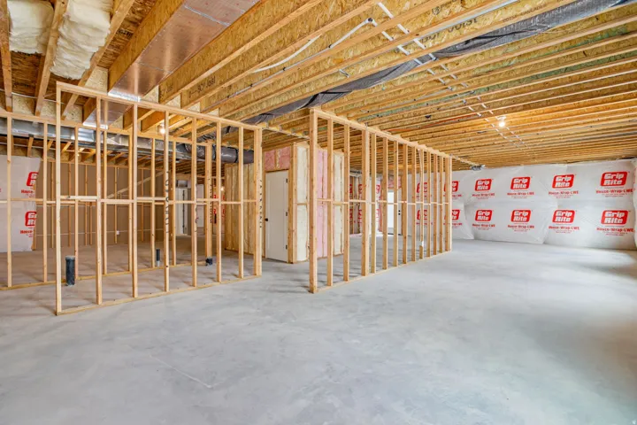 Unfinished basement featuring exposed wood framing, concrete flooring, and partial wall insulation