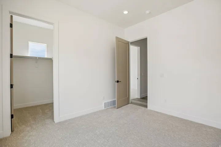Recessed lighting, light-colored carpeting, and a built-in closet with a window