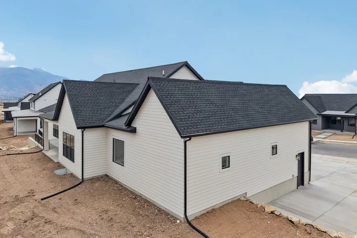 White horizontal siding exterior with black trim, dark shingle roof, multiple gables, and a concrete driveway