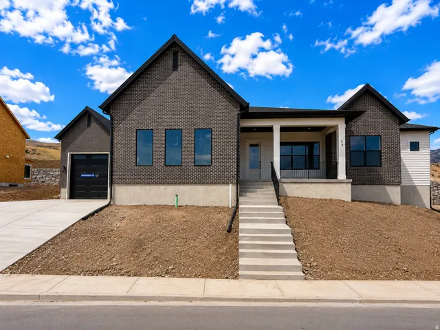 Contemporary single-family residence featuring a dark brick facade, a covered front porch with white columns, and black-framed windows