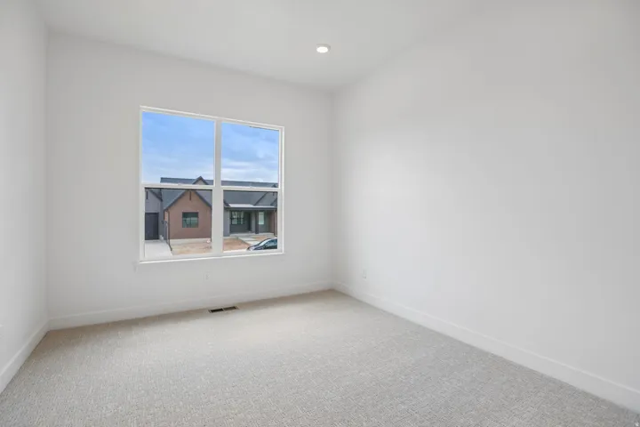 Recessed ceiling lighting, large window, neutral wall paint, light-colored carpet flooring, crisp white trim