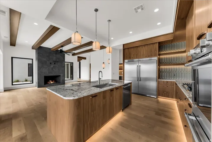 Gourmet kitchen with stainless steel appliances, wood-finish cabinetry, granite island with undermount sink, and wood-finish flooring