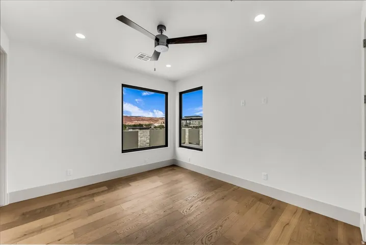 Wood-finish flooring with crisp white walls, recessed ceiling lighting, and a dark-bladed ceiling fan