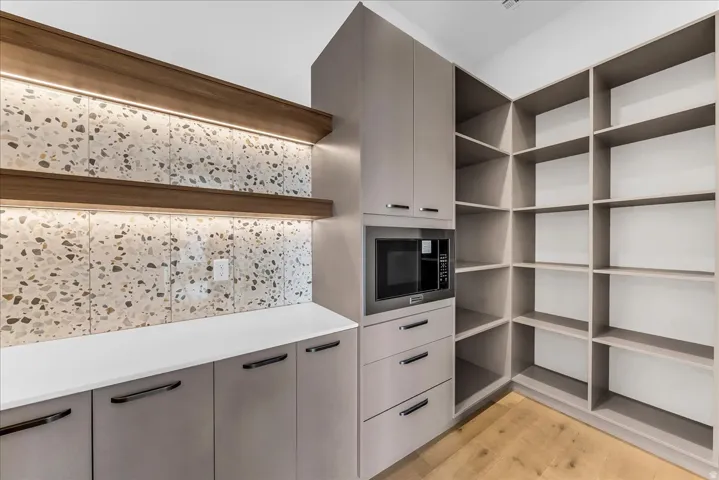 Built-in shelving, integrated microwave, wood-finish flooring, accent lighting, and light-toned cabinetry