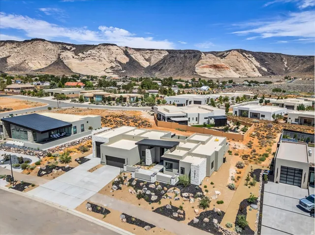 Modern architectural residence featuring a flat roofline, integrated two-car garage, concrete driveway, and desert-adapted landscaping with rock accents