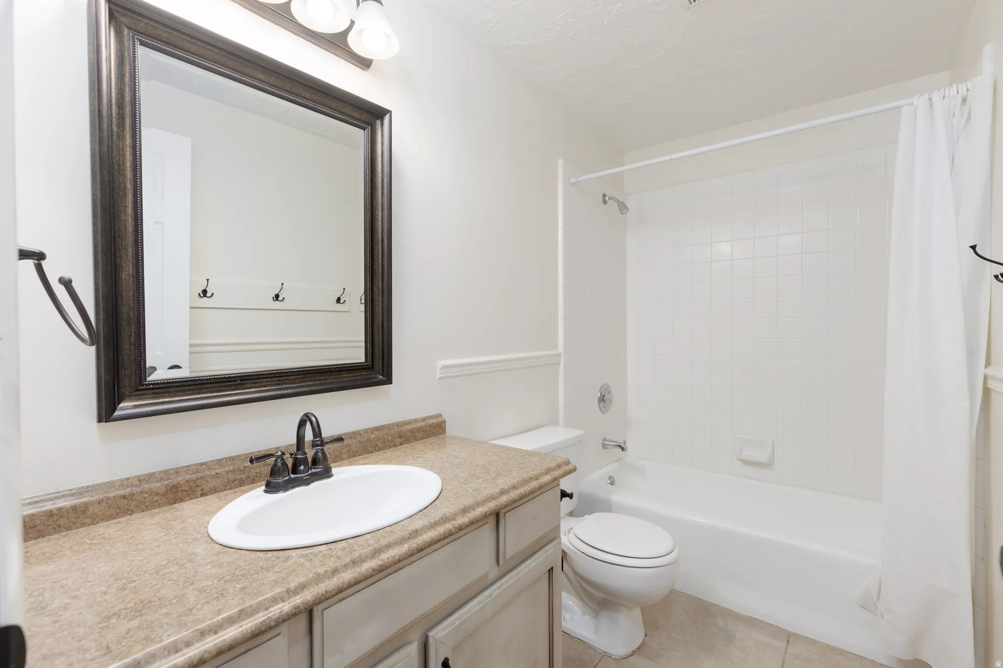 Bathroom featuring a single vanity with an oval sink, dark bronze-finish faucet, and a large framed mirror