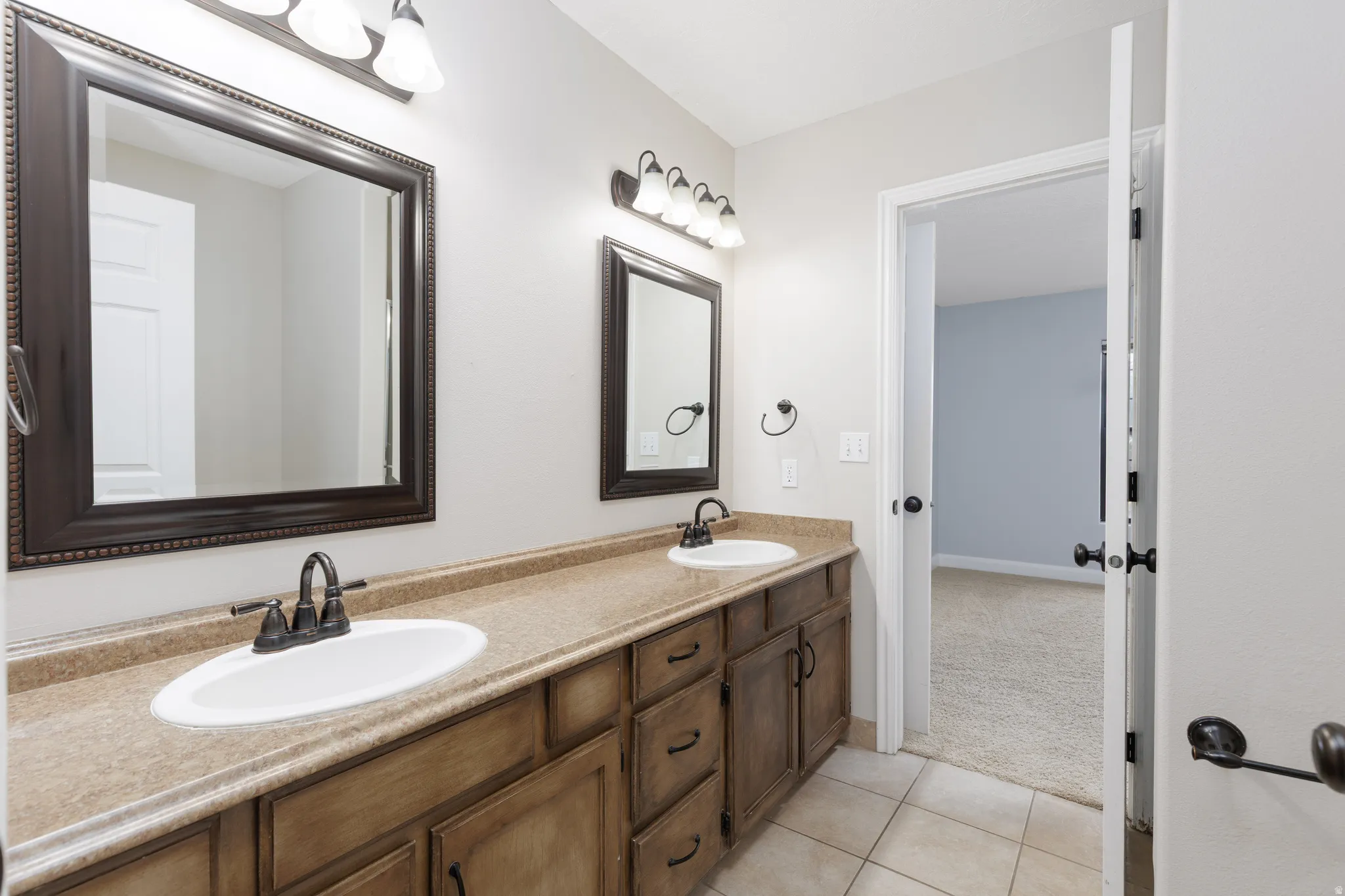 Dual vanity featuring integrated sinks, bronze-finish faucets, and framed mirrors