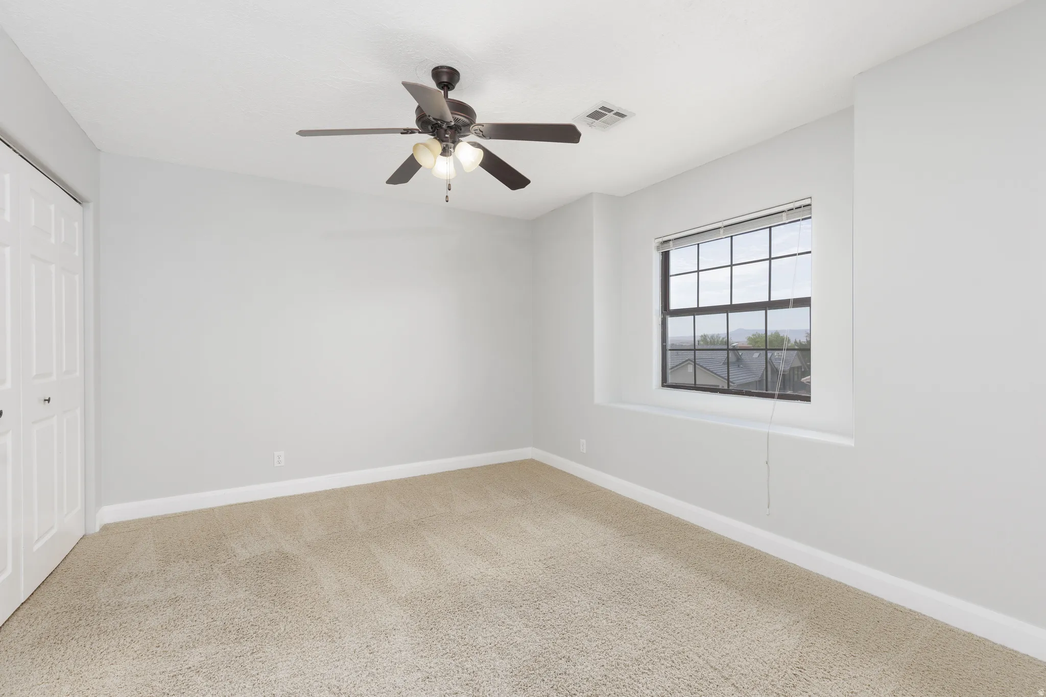 Carpeted flooring, a window with horizontal blinds, and a built-in ceiling fan with integrated lighting