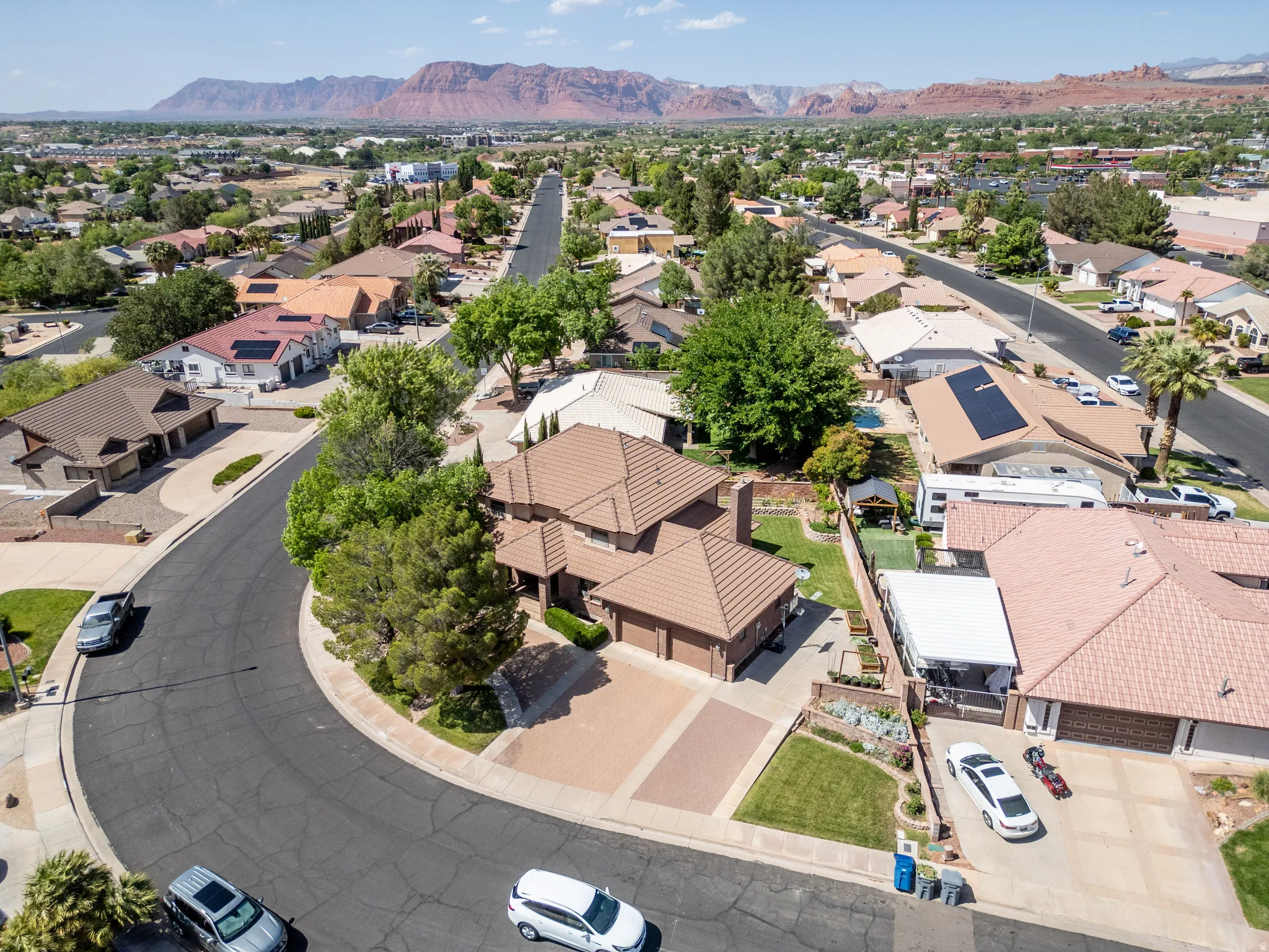 Multi-level residential property with a tile roof, paved driveway, and mature landscaping