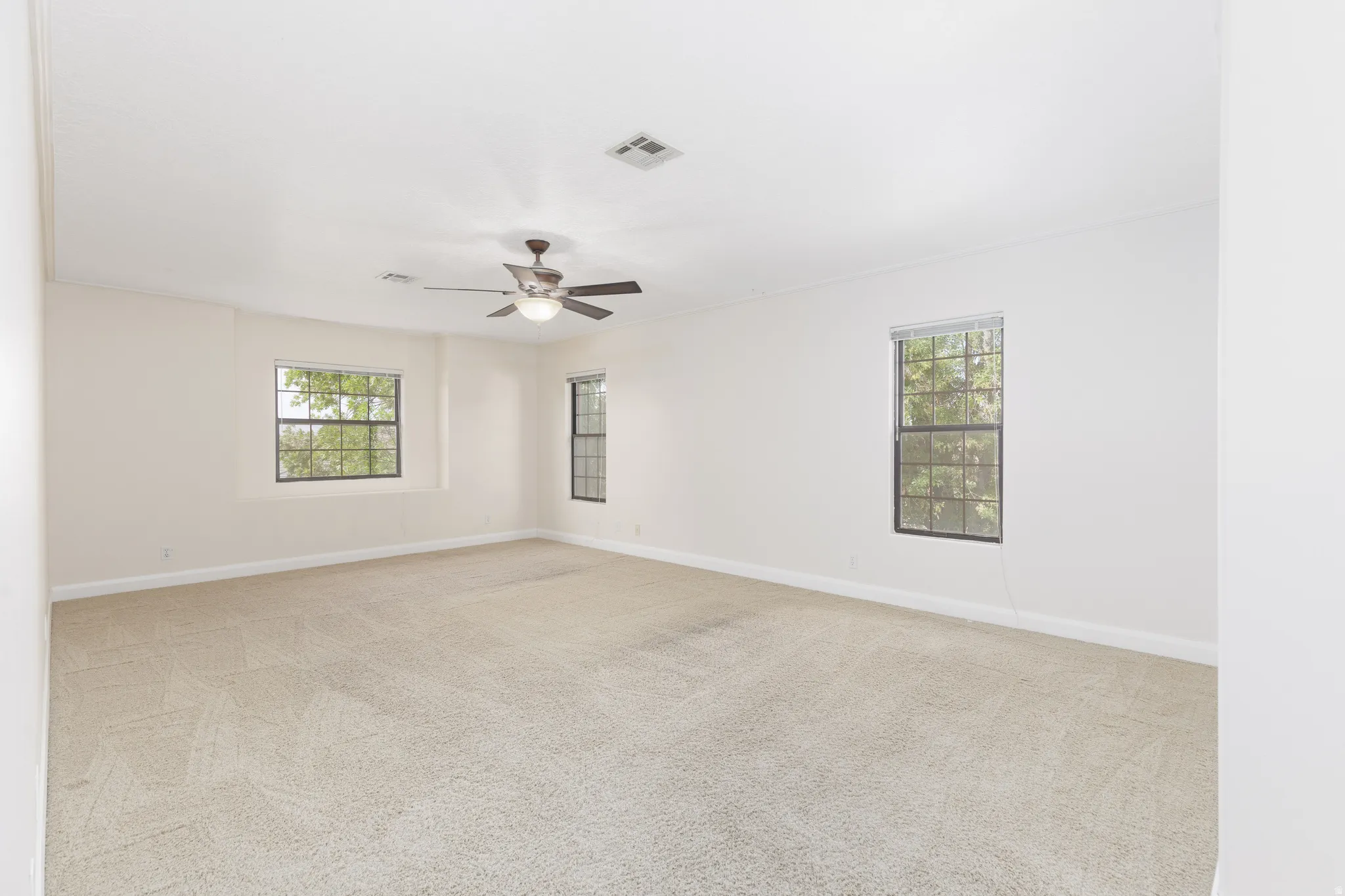 Carpeted interior with neutral wall finish, multiple windows, and a ceiling fan with integrated lighting