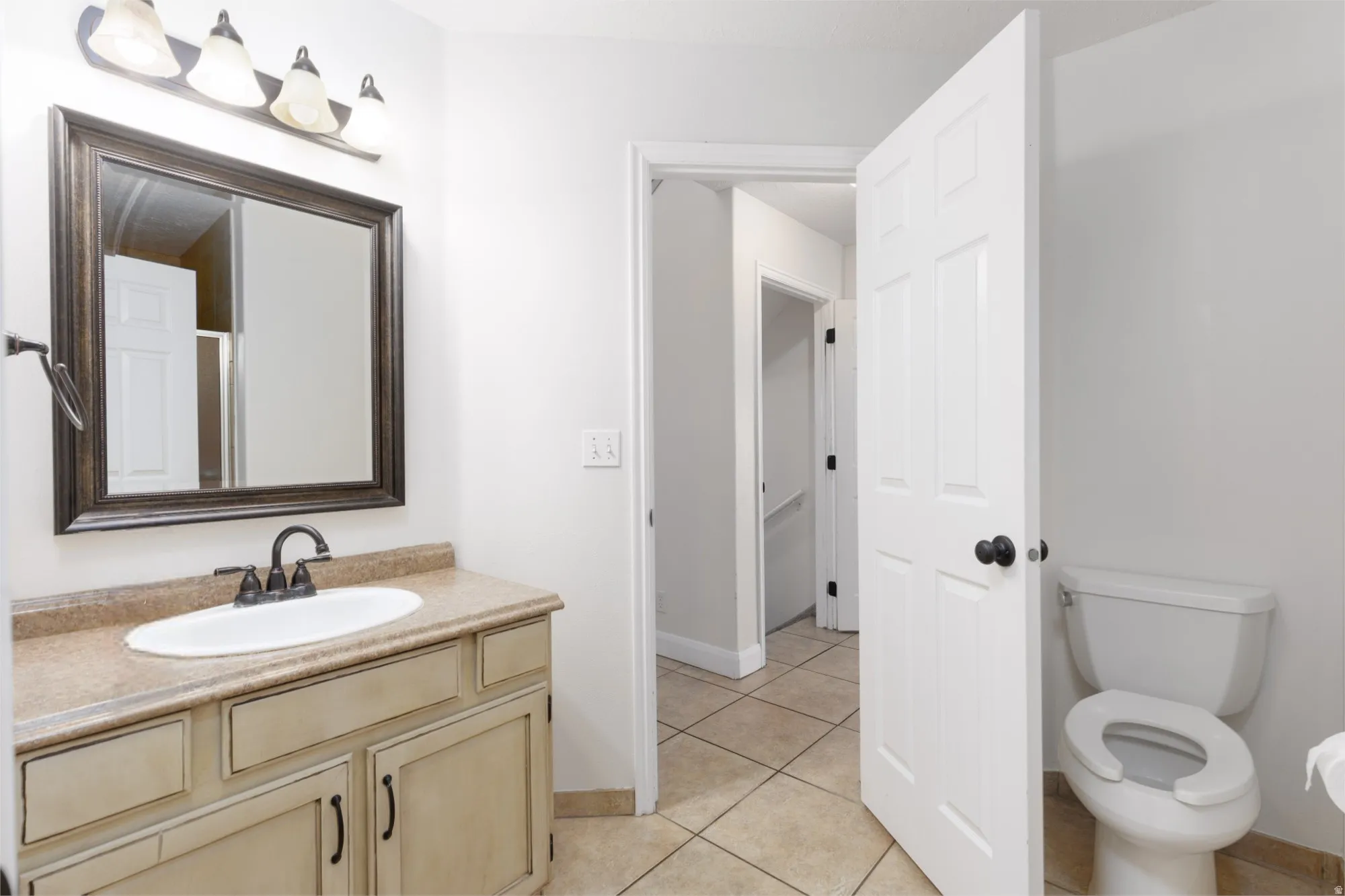 Vanity with integrated sink, framed mirror, and a three-light fixture