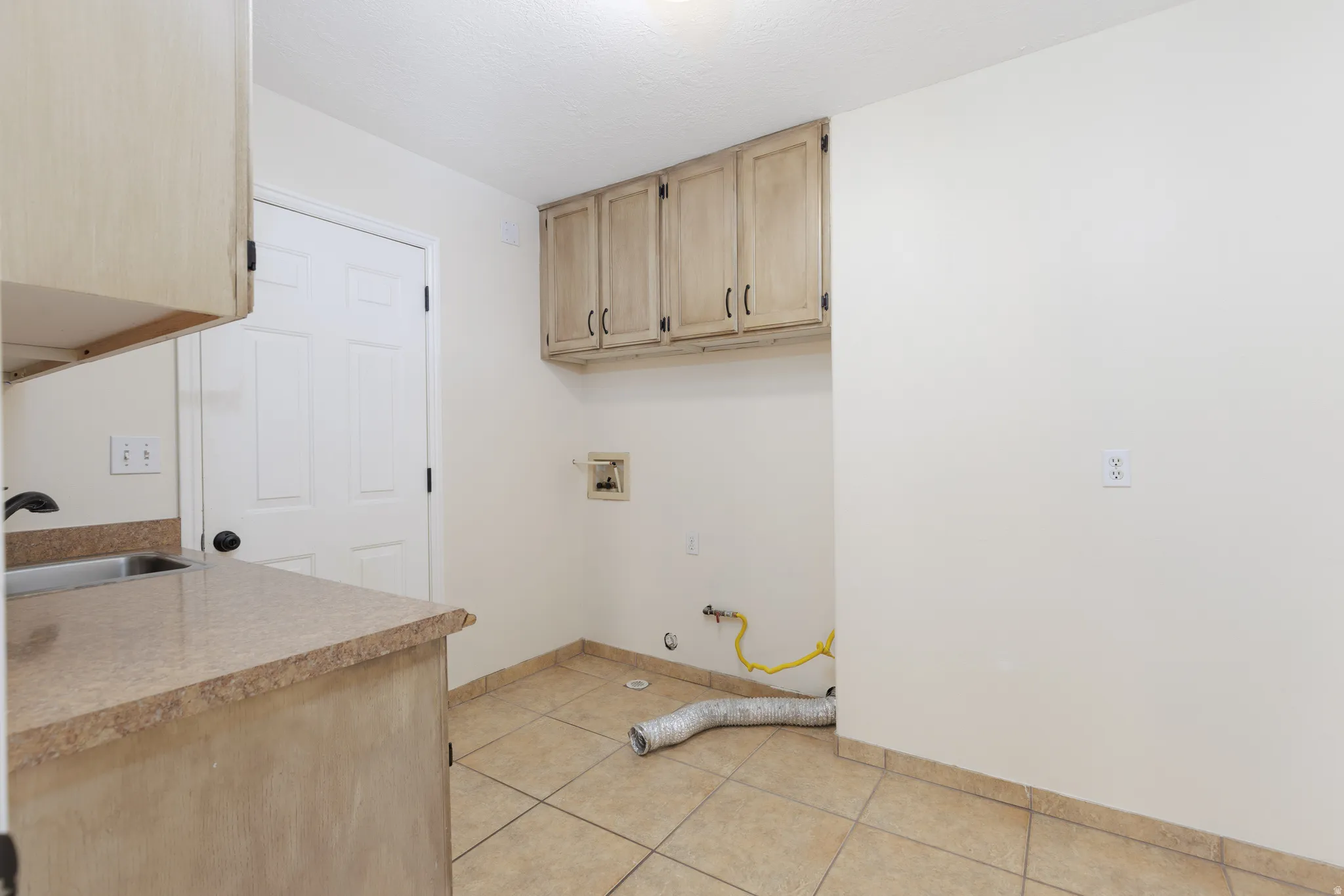 Utility room with built-in cabinetry, an integrated sink, and tiled flooring