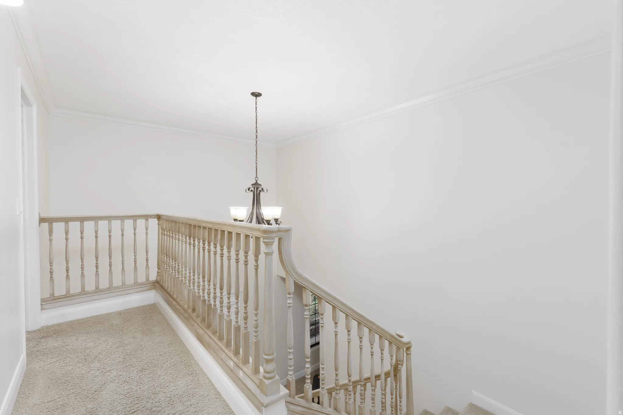 Stairway with carpeted treads and risers, featuring a light wood-finish balustrade and newel post