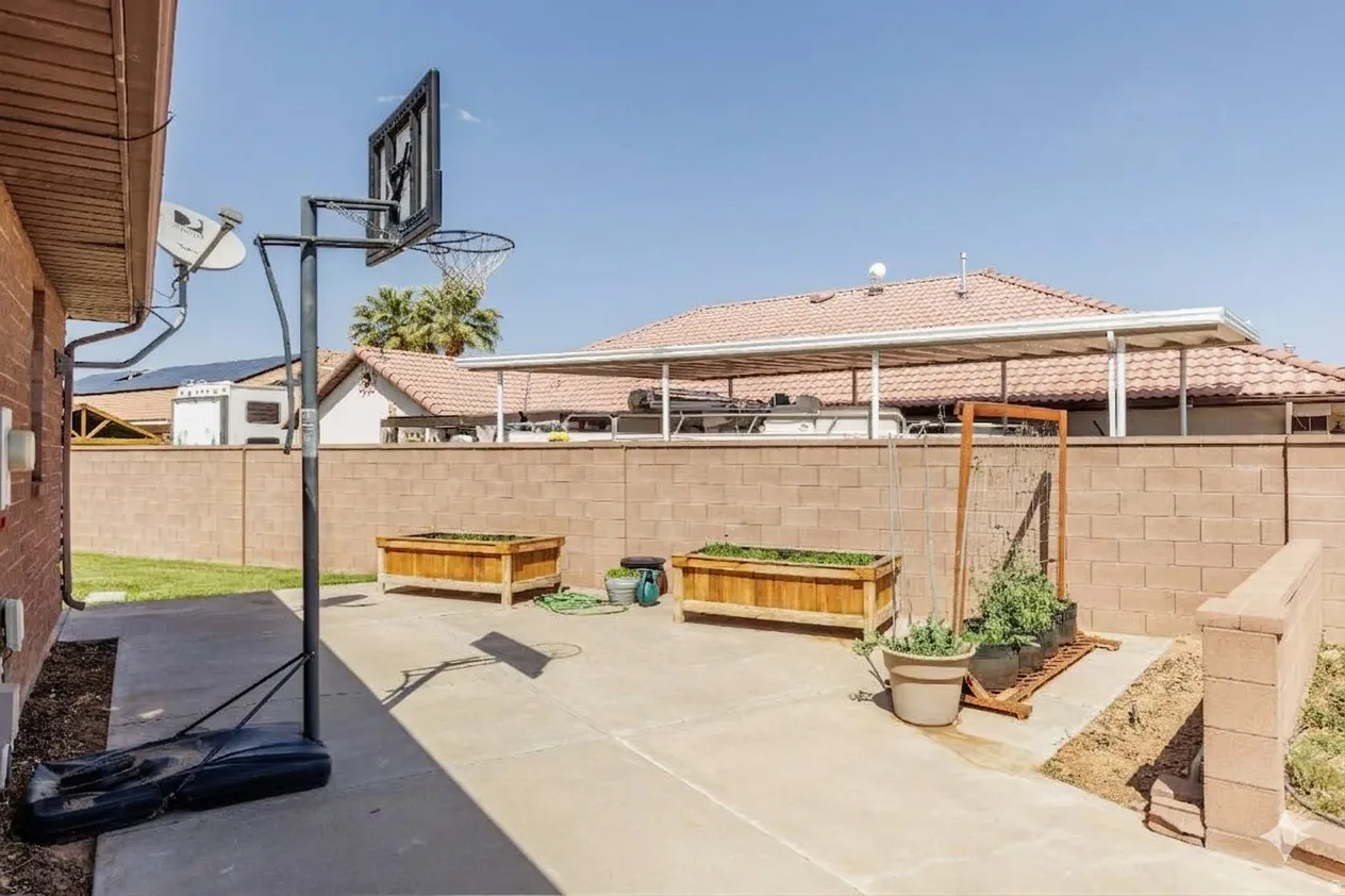 Concrete patio with two raised garden beds and a block wall perimeter