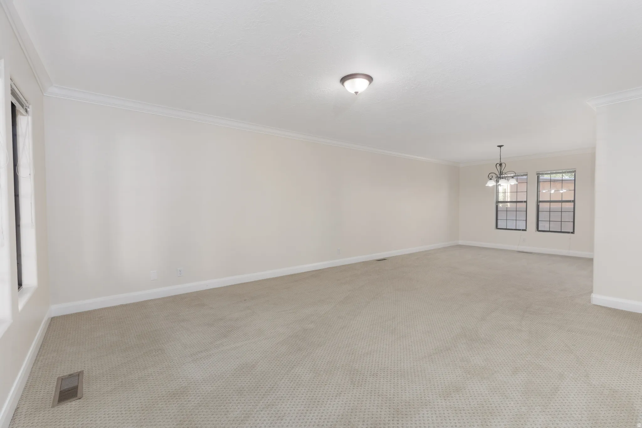 Spacious interior with neutral carpeting, crown molding, and multiple windows