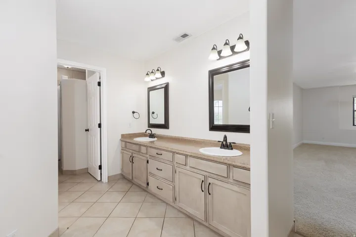 Dual vanity with light-toned cabinetry, two rectangular mirrors, and individual sconce lighting