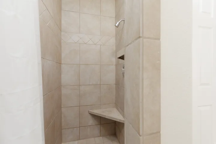 Tile-surround shower with a built-in corner bench, recessed niche, and a decorative tile band accent