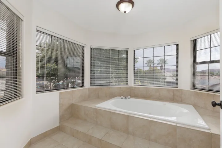 Built-in soaking tub with tile surround, bay window configuration, and recessed ceiling light fixture