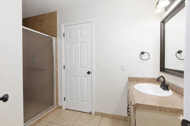 Shower enclosure with a frosted glass panel, tiled walls, and tiled flooring