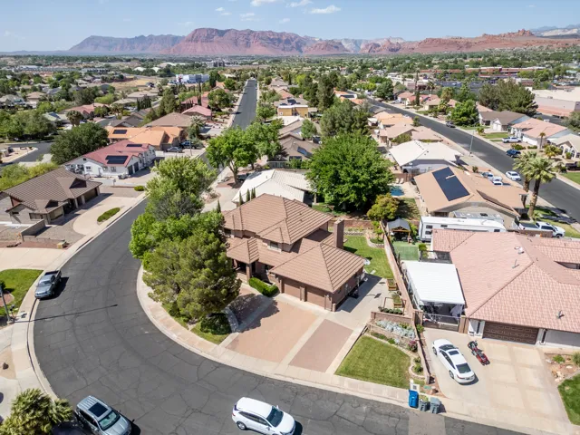 Multi-level residential property with a tile roof, paved driveway, and mature landscaping