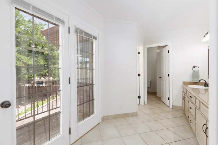 French doors with internal grilles, tile flooring, built-in vanity with single basin, wall-mounted light fixture, and mirrored wall