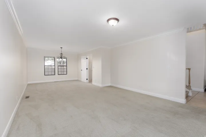 Carpeted flooring, crown molding, two gridded windows, a decorative chandelier, and a semi-flush ceiling light fixture