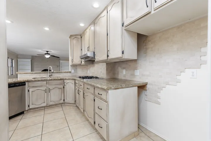 Kitchen featuring light-toned cabinetry, granite-finish countertops, stainless steel dishwasher, gas cooktop, and recessed lighting