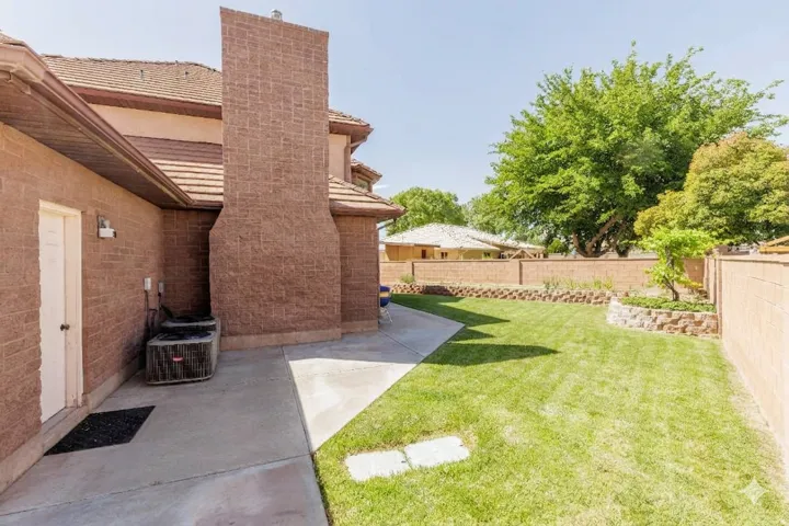 Expansive backyard featuring a manicured lawn, concrete pathway, and raised planters