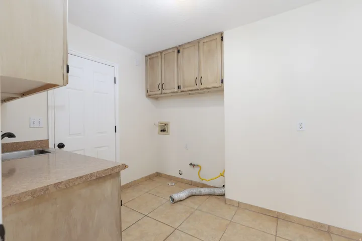 Utility room with built-in cabinetry, an integrated sink, and tiled flooring