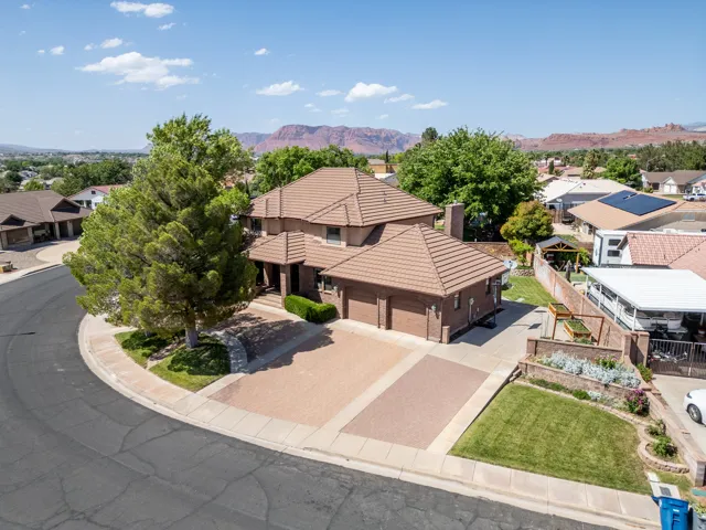 Brick exterior with a tiled roof, paver driveway, and an integrated two-car garage
