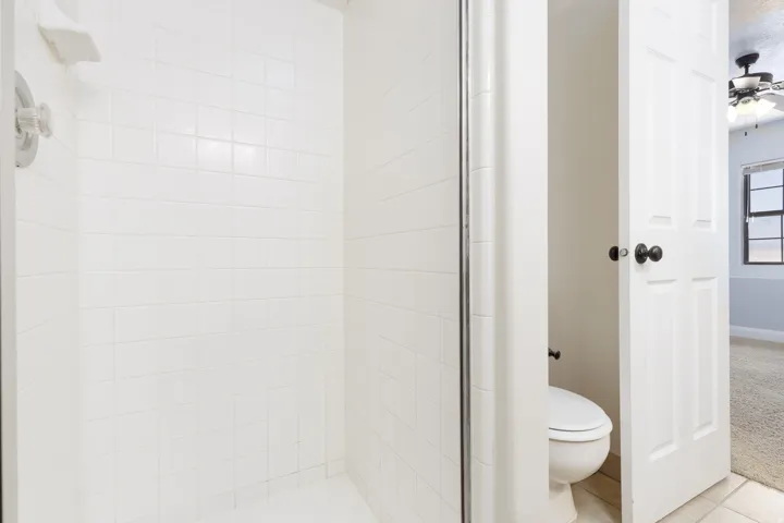 White tiled shower with chrome fixtures and glass enclosure