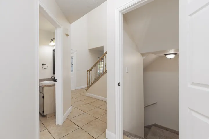 Two-story foyer with tile flooring, wood staircase, and an attached vanity with a single basin sink
