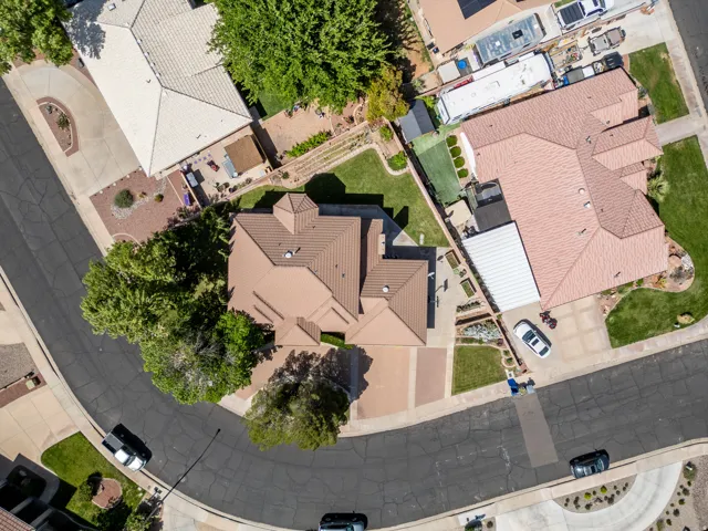 Single-story property with a tile roof, paved driveway, mature landscaping, and a fenced yard