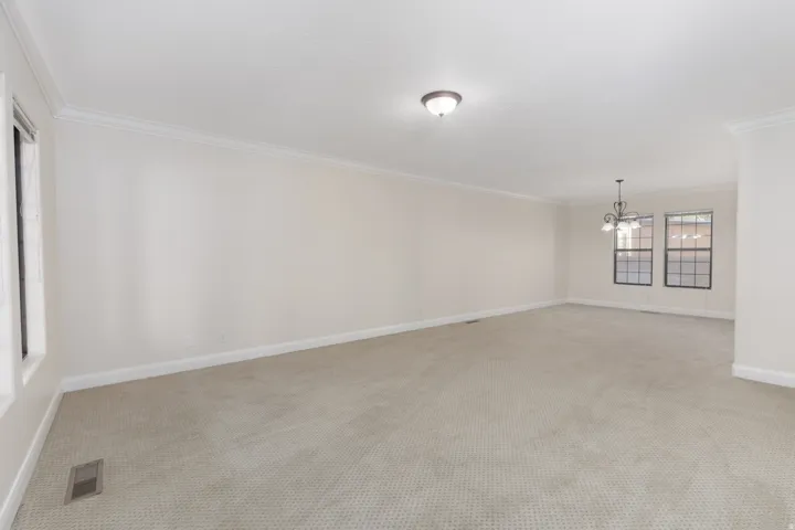Spacious interior with neutral carpeting, crown molding, and multiple windows