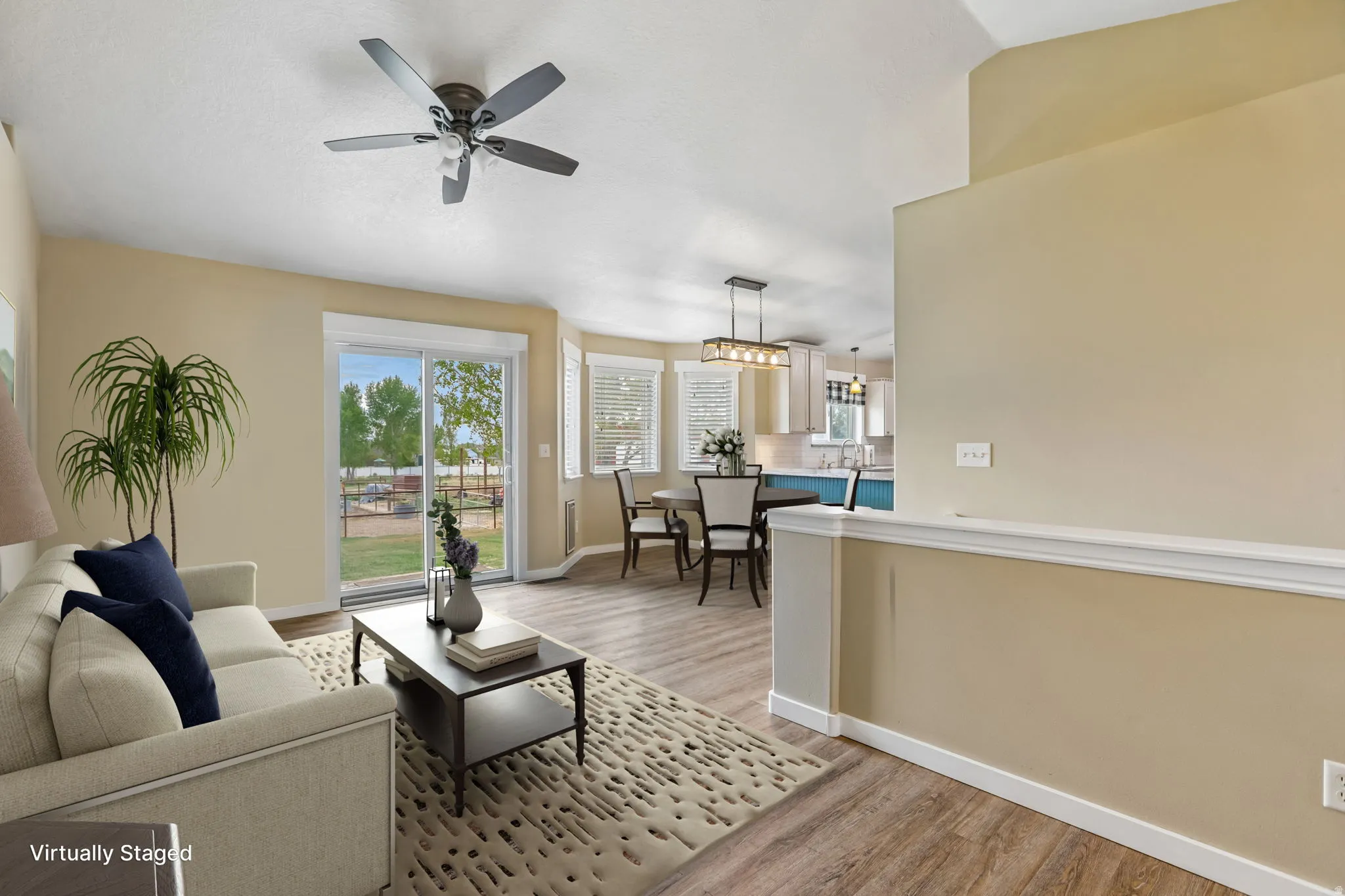 Sliding glass door, ceiling fan, wood-finish flooring, half-wall partition, and window with blinds