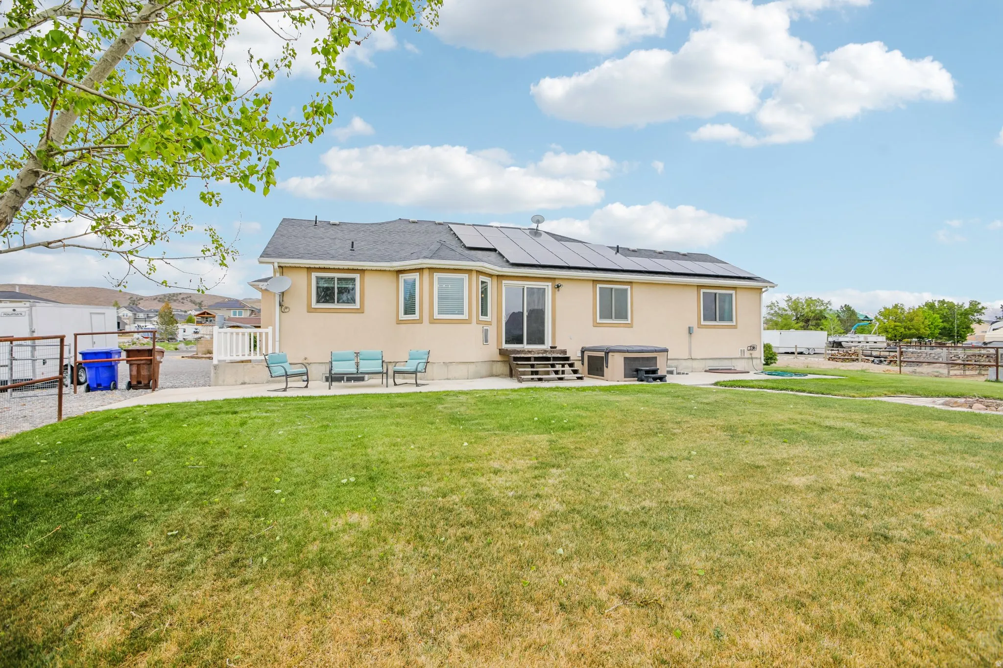 Back of property featuring a patio, roof mounted solar panels, stucco siding, and entry steps