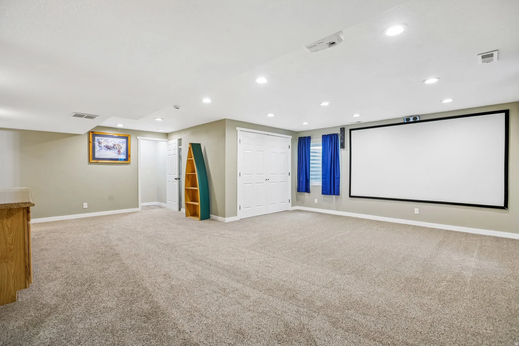 Cinema room with light colored carpet and recessed lighting