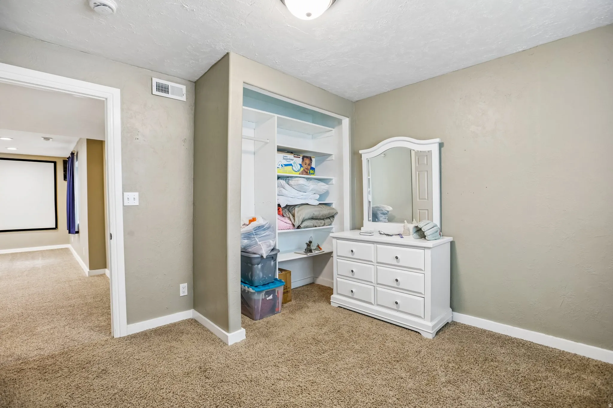 Bedroom featuring light colored carpet, a textured wall, and a textured ceiling