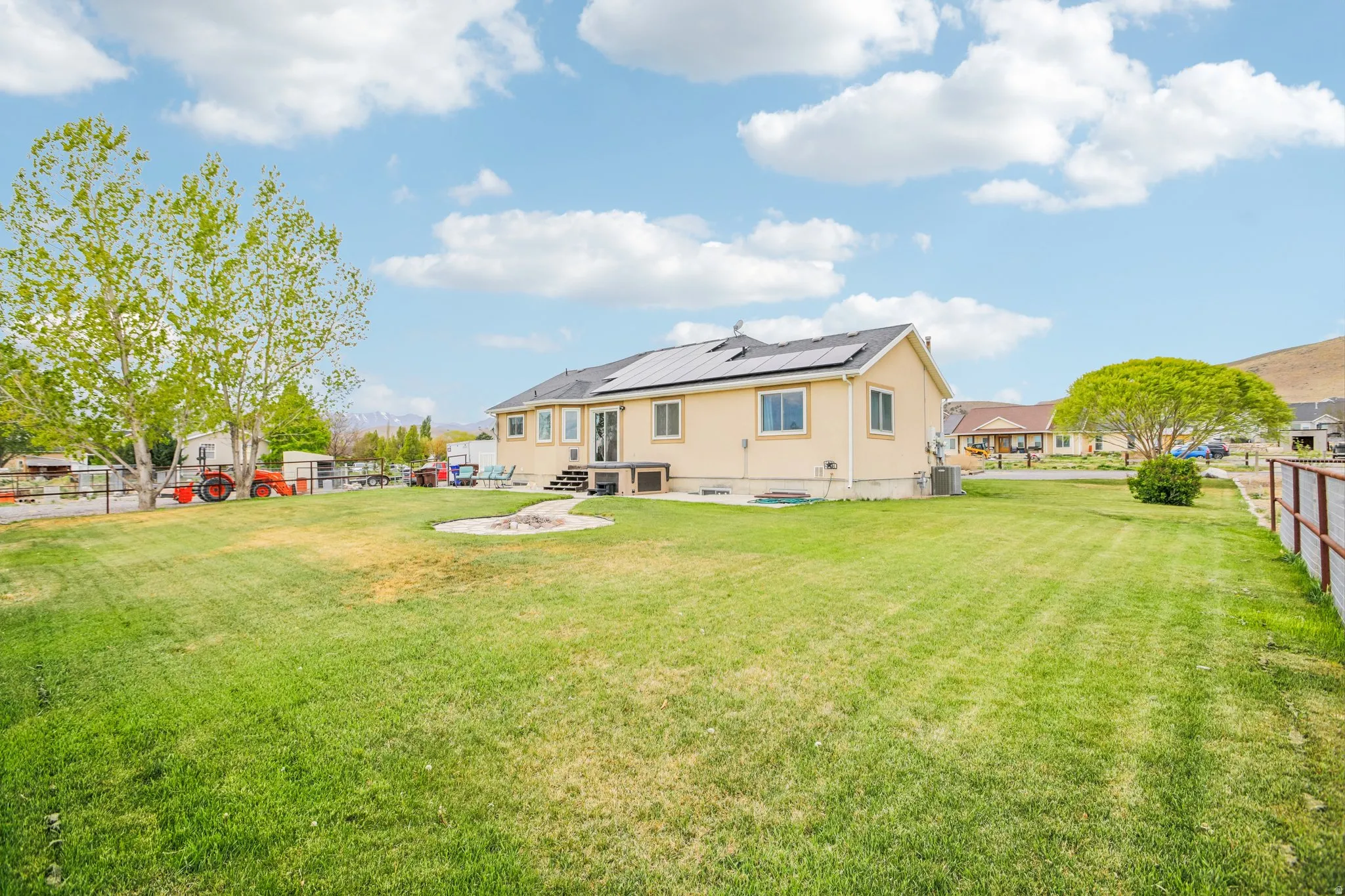 Back of property with a fenced backyard, solar panels, a patio area, and a residential view